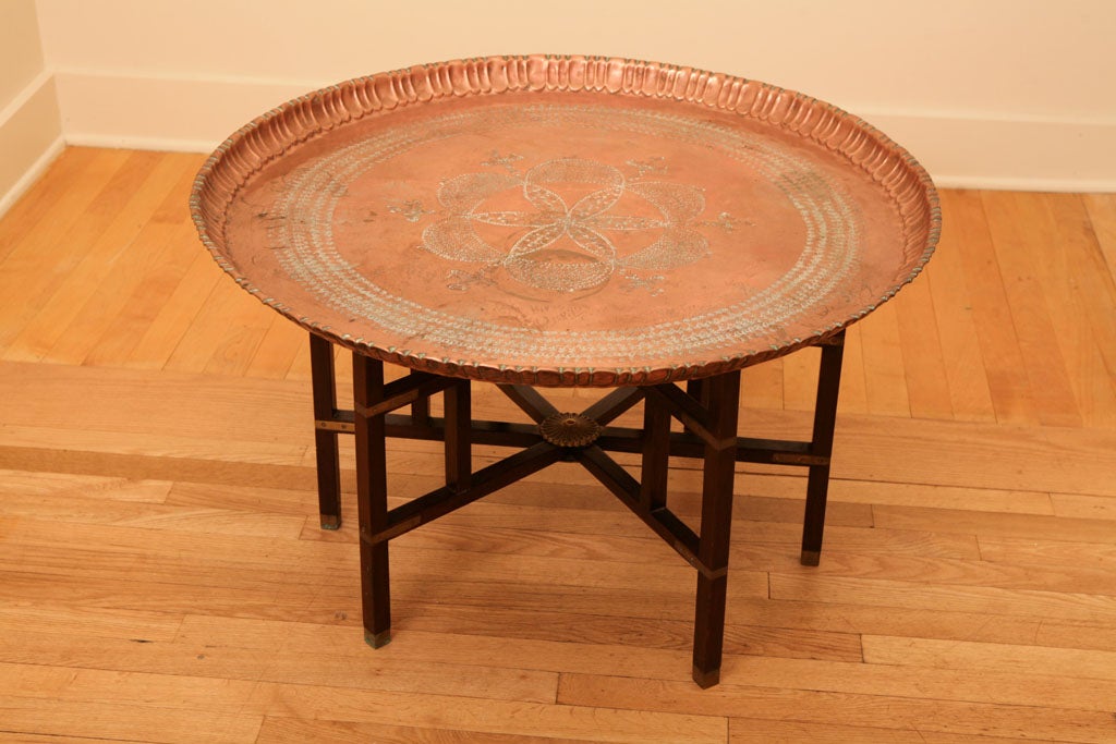 Folding base with hammered brass serving tray. Has pie crust<br />
edges on tray and decorative design medallions on leg supports.