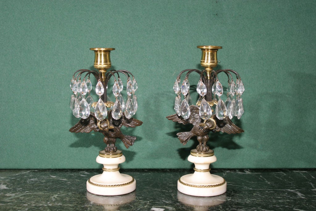 Very fine pair of Regency ormolu, bronze and cut crystal candlesticks, the diamond cut crystal urn-form nozzle above a star and prism-hung pierced bronze anthemia-banded canopy, supported by a gilt bronze spread-winged eagle with a coiled serpent in
