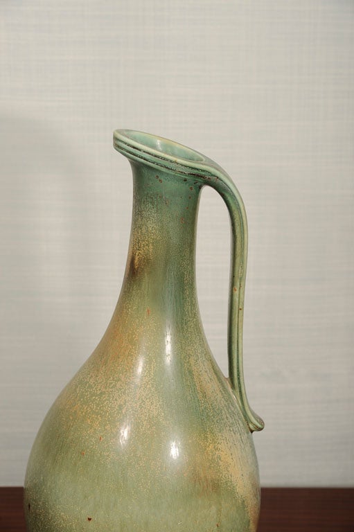 Handmade stoneware pitcher with applied handle and pale green feather glaze. Signed on underside.