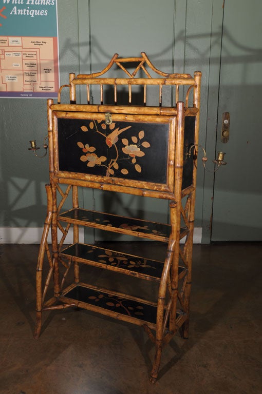 An English Bamboo secretary featuring japan-lacquered panels on the front, sides, and shelves with decorative Chinoiserie designs of birds and flowers. Many features call to mind the best of the Aesthetic Movement such as the fretting of the gallery