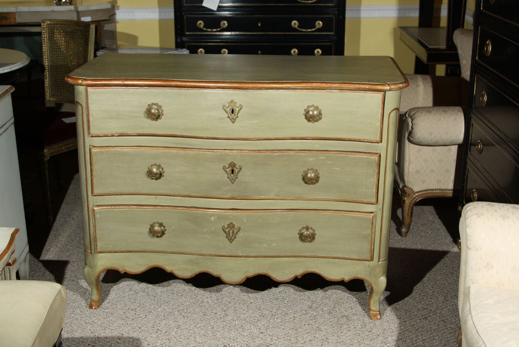 A very charming French commode, circa 19th century, overall green distress-painted, the beveled serpentine top over a conforming case of three long banded drawers, standing on scalloped apron and cabriole legs. The interior drawers all lined.