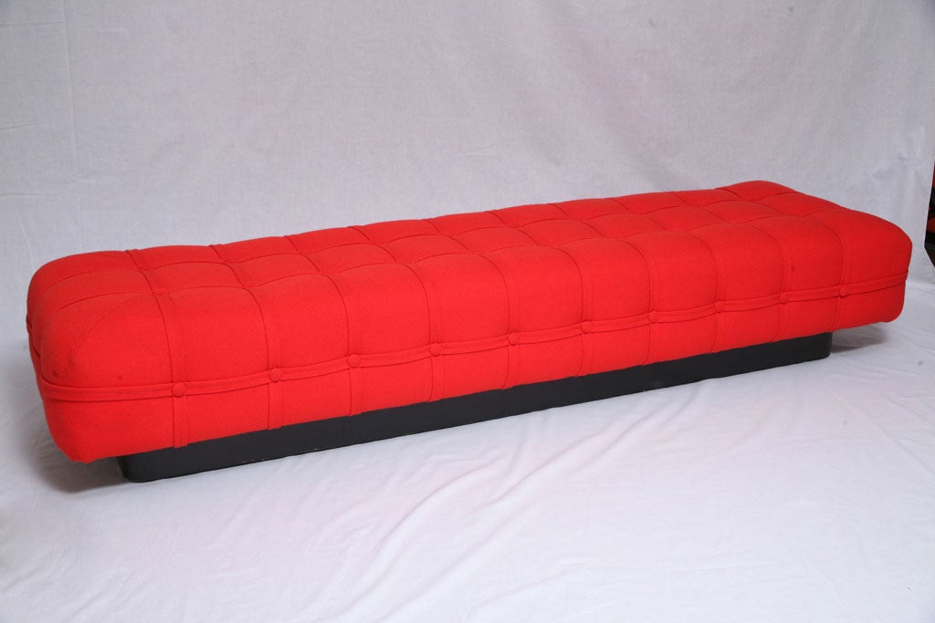 This long, sleek bench measures almost 7' long and is beautifully finished in button tufted red wool upholstery with flat cable details throughout. Black lacquered plinth base.<br />
<br />
(style: Florence Knoll, Milo Baughman)