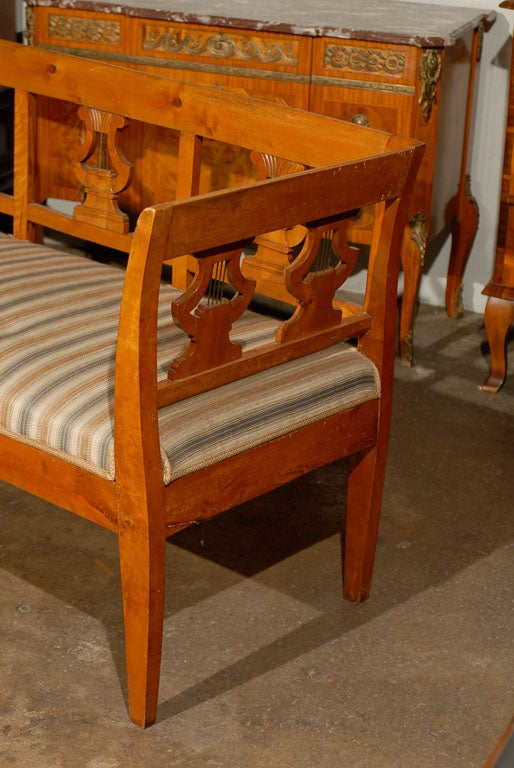 A mid-19th century Swedish Karl Johan bench or settee made of birchwood with lyre carved splats, slightly slanted arms and tapered legs. The Karl Johan Period follows the Gustavian period in Sweden.