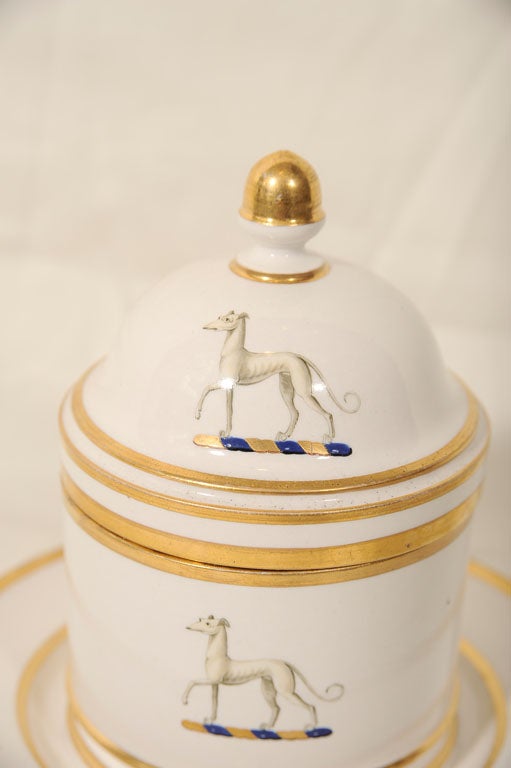 A Flight & Barr Worcester honey pot, attached stand and cover with an armorial featuring a greyhound. The finial is in the form of an acorn. The bottom of the stand is marked with an impressed FBB below a crown