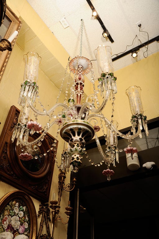 This Bohemian glass chandelier has six electrified candle arms with clear glass hurricane shades with gilding, and a center stem with cased glass sections and glass bellflowers. Wired for use in the U.S.
Stock number: L84.