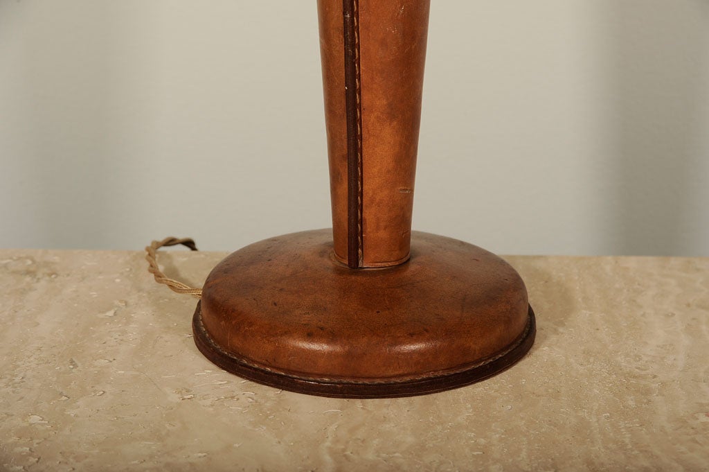 Elegant table lamp in tobacco leather with stitching to edge.