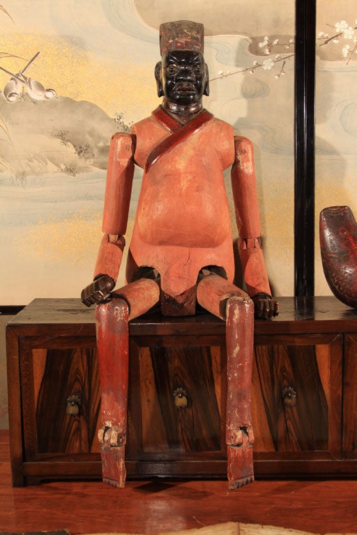 Large Chinese puppet carved of wood and with articulating arms, legs, elbows and knees. Puppets like these were elaborately dressed and paraded through towns and villages of Southwestern China to honor ancestors. An unusual example with face and