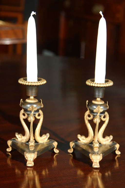 A pair of English Regency bronze candlesticks with dolphin motifs and ormolu mounts.