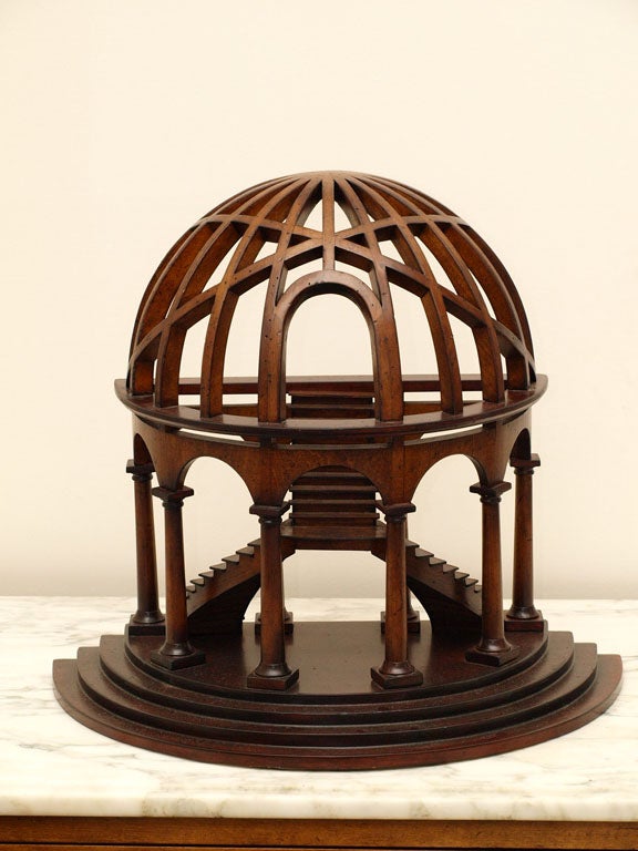 Attractive tabletop architectural model in walnut; two curving stairs rise from a stepped plinth to a central landing, from which a third straight stair rises; semi-circular columns and arches support the dome