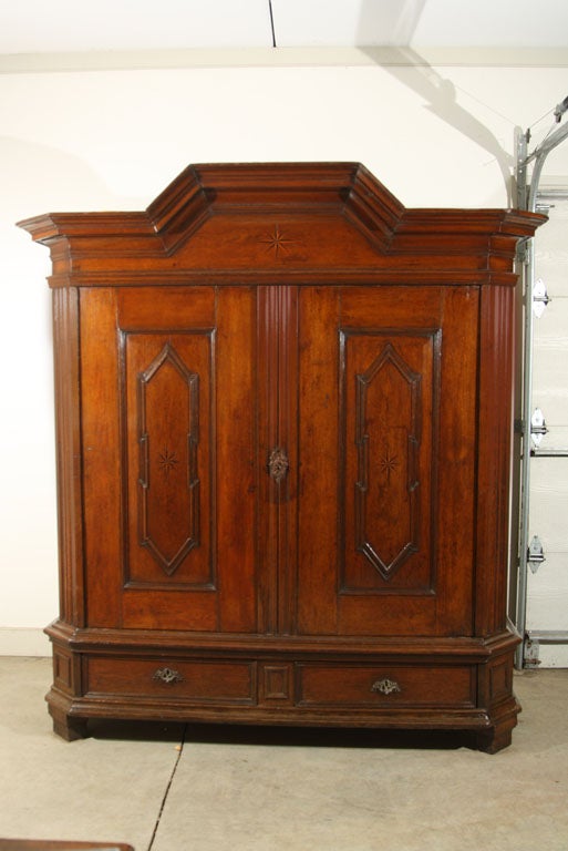 German oak kas with bracket top, raised panel doors, chamfered and fluted corners, two drawers, block feet. Compass inlay on frieze and doors. Unique raised panel sides are a graceful curvilinear addition to the overall rectilinear appearance of
