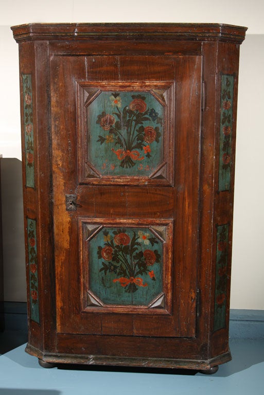 Dutch, painted pine kas with single door having recessed panel doors painted with floral bouquets. Chamfered corners continue the floral motif on faux grain-painted background. Original paint.