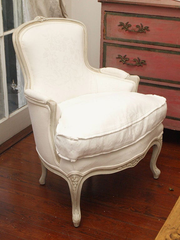 Beautiful Antique Bergere Chair in Vintage White Matelasse fabric, painted in a perfectly patinaed french gray.  Small carved roses, and cabriole legs.  We retied springs, put the original horse hair, and new cotton. The seat is a thick, soft down