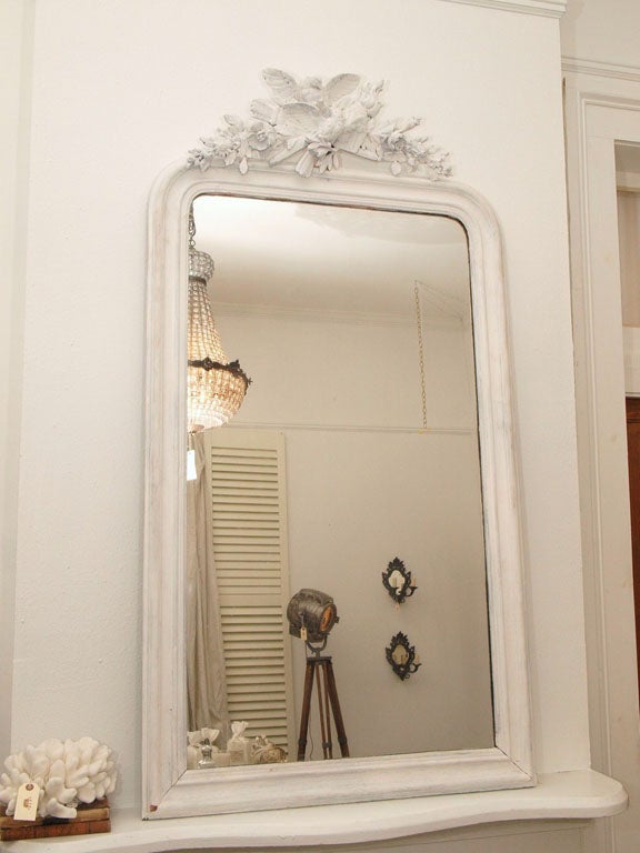 White on white. It is amazing how the eye naturally looks to the differences in texture and carvings when looking at a monotone color. This is a spectacular vision in white -- an antique Louis Philippe style mirror with a gorgeous hand carved