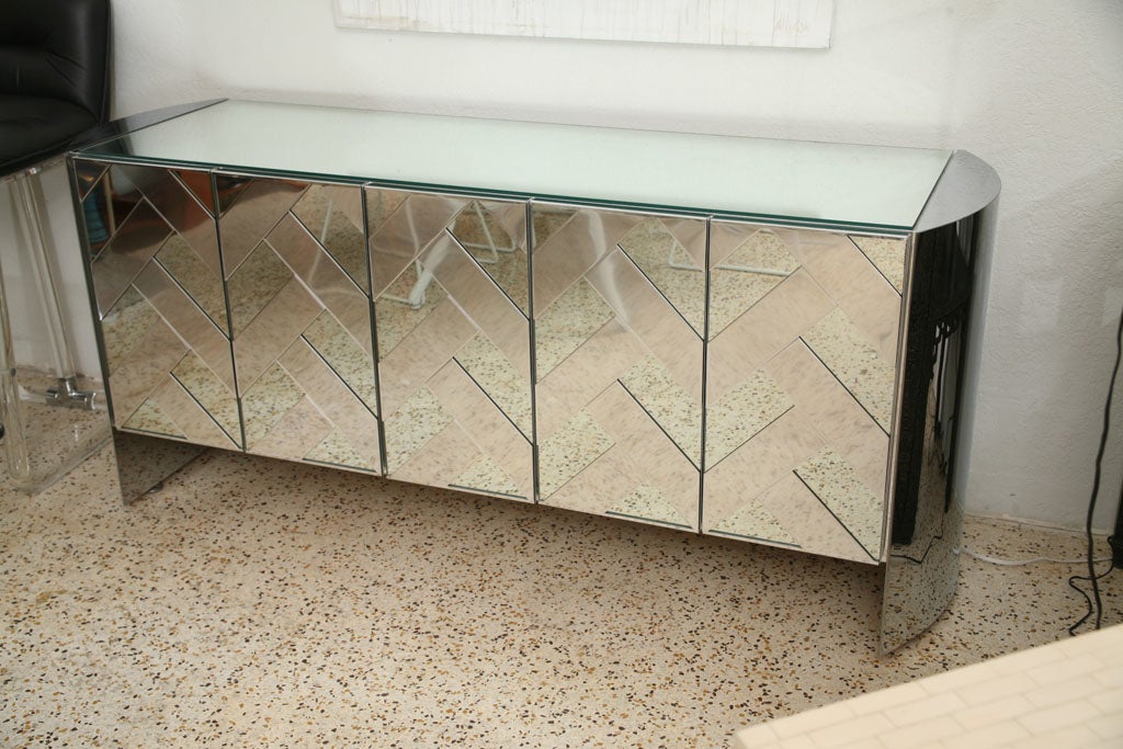 Superior Ello construction meets 70's High Glamour! Polished steel caps both ends of this buffet, and combines with mirror to form a basket-weave pattern across the touch-release doors. Mirrored top. Ice, ice, Baby!