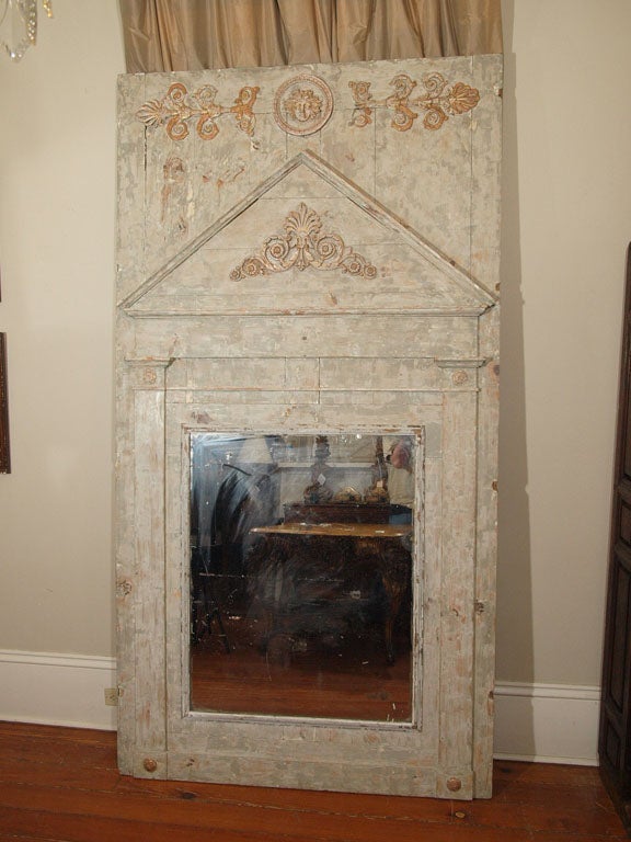 A polychrome and gilt Empire style mirror flanked with columns supporting a palmette embellished pediment.