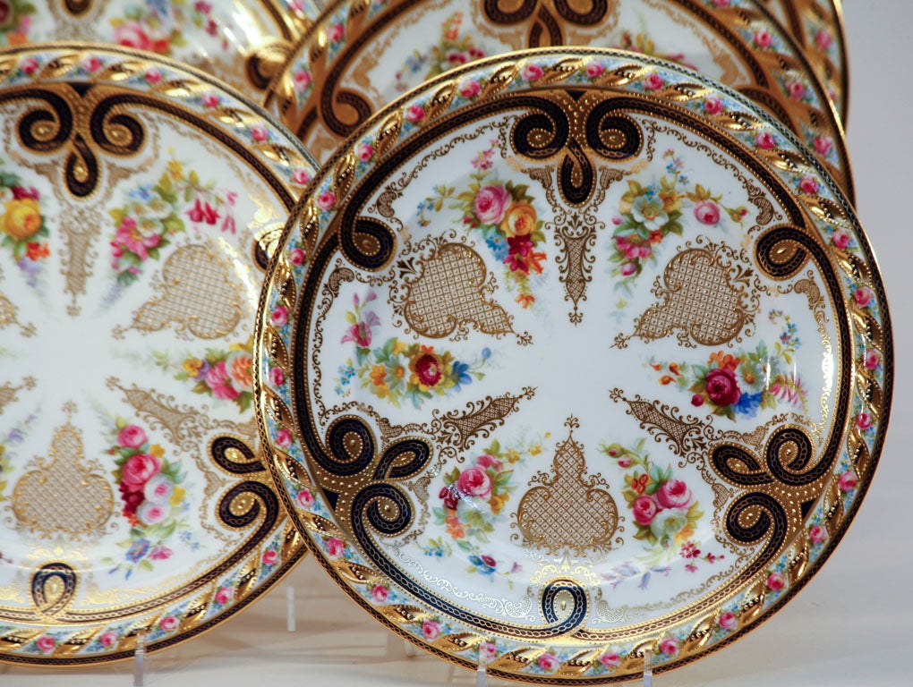 Ce jeu de 12 assiettes de service/présentation Cauldon illustre le meilleur de la décoration anglaise. La bordure est moulée en relief et entièrement peinte à la main dans les moindres détails. Chaque assiette est décorée de façon unique avec des
