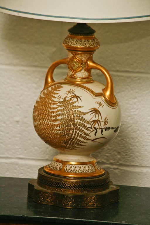 Here is a charming ivory colored ceramic lamp with an embossed gold fern motif. Finished on both sides, the form is mounted on a scalloped brass base with fretwork.