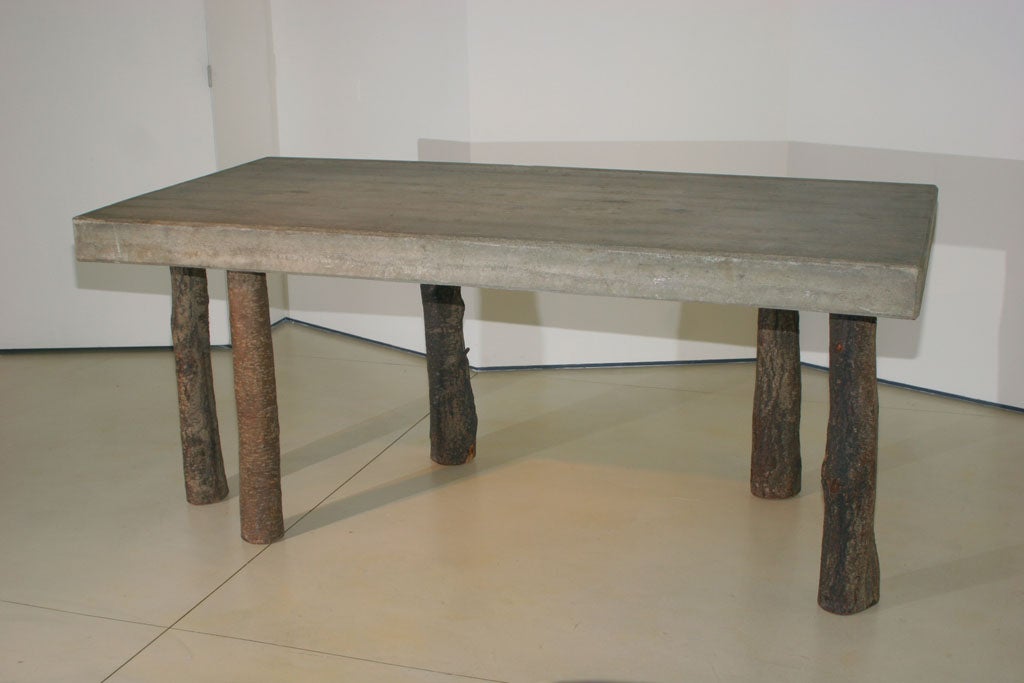 A concrete table with tree trunk legs by Jens Peter Schmid.