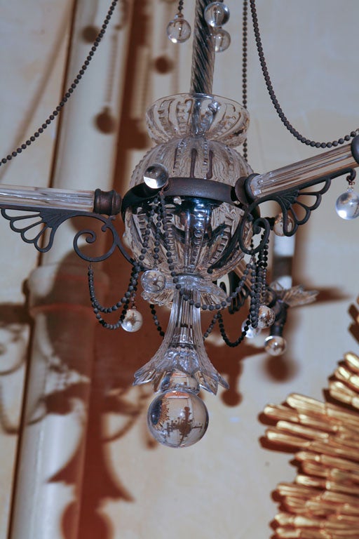 This very unusual gasolier in the aesthetic movement style has been converted to electric lighting. Sparse but highly decorative the basic glass shape is enlivened with bronze athenaeum and ring spacers with solid glass balls hung from bronze bead