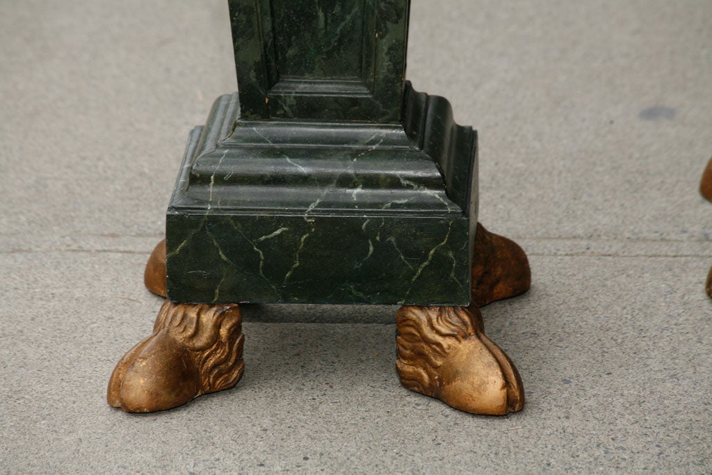 This pair of French pedestals exhibit a large and highly decorative three dimensional carved wood application of rams heads, garlanded laurel and berries and rams feet all gilded. This applied to the faux marbled surface creates a dramatic old world