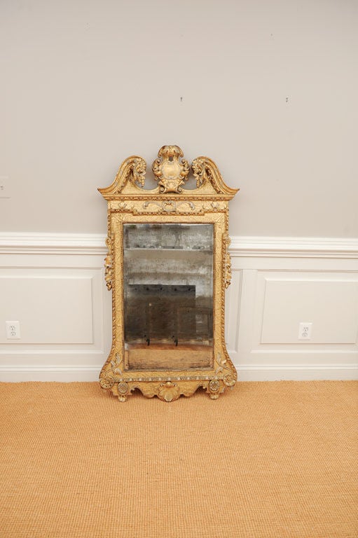 Wonderfully carved George II Giltwood Pier Mirror, in the manner of William Kent, with a swan's neck pediment flanking a crest, the sides with carved acorns and leaves flanking original mirror plate above a shaped apron.

View our complete