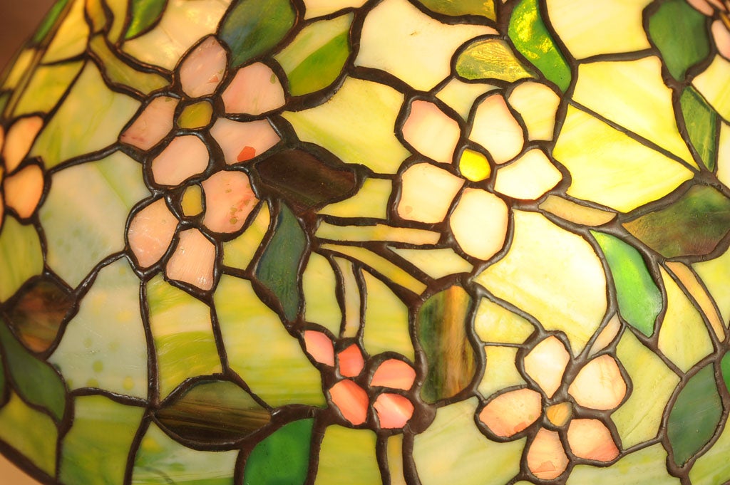 A very special example of the Tiffany Apple Blossom pattern lamp that we are offering.  There is a dash after the signature on the shade, which means it was a special order.  Besides having the usual wonderful Tiffany glass, the flowers contain
