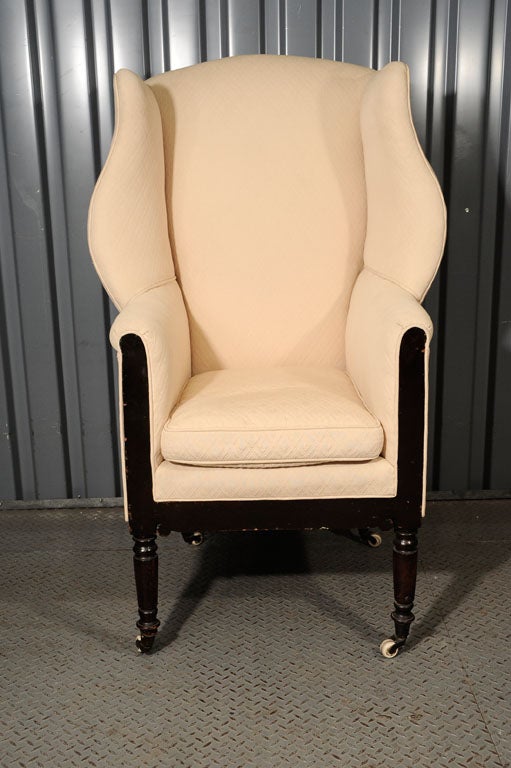 William IV style wingback chair. Turned mahogany legs on casters.