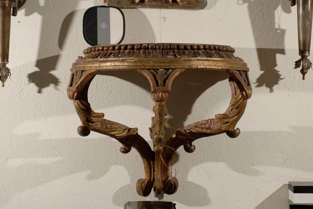 A large size carved and painted 19th century bracket. This Italian painted wood bracket with traces of gilding is made of a carved top supported by three volutes with acanthus leaves ornaments.