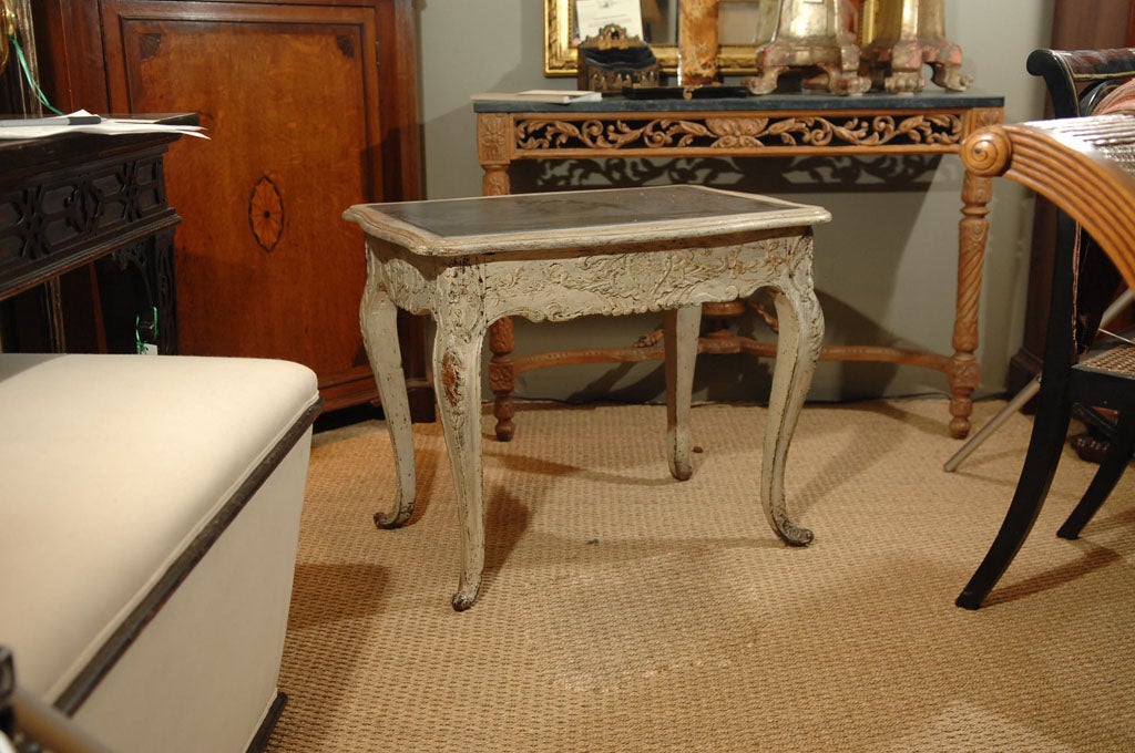 A fine French carved low or side table featuring a white wash body with an inset black slate top. 
The serpentine top over a carved floral frieze adjoined to four cabriole legs.