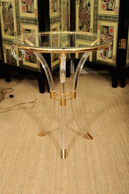 Lucite and brass plated Gueridon have glass tops and scrolling down-swept legs.