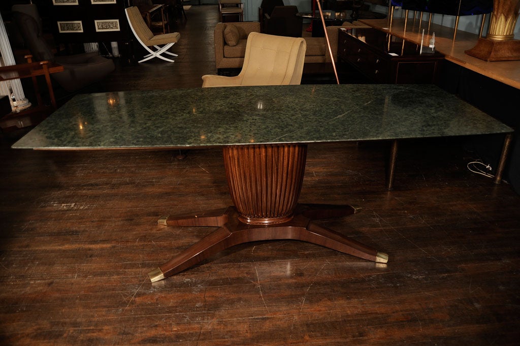 Substantial dining table of dark stained mahogany.  Ribbed, lyre-shaped pedestal base and splayed tapering feet with brass sabots.  Beautiful, highly figured dark green marble top that tapers to a very thin edge.