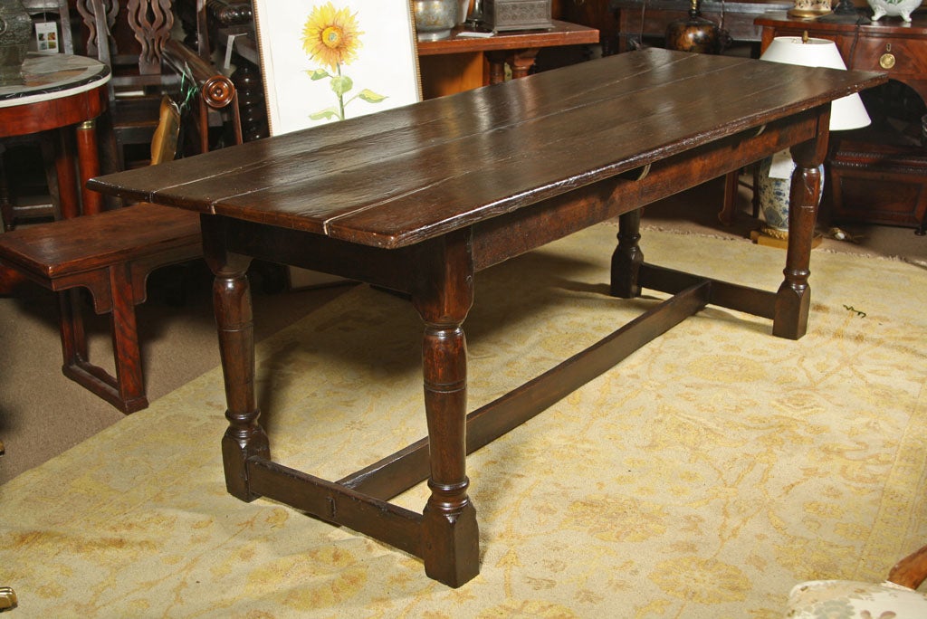 A Jacobean period oak plank table with turned legs and simple stretcher having a wonderful patina with minor alterations.