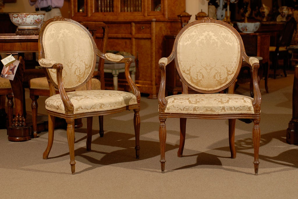 A fine pair of George III period arm chairs in the French taste with rosette detail above circular back, shaped seat and fluted legs. The chairs dating the end of the 18th century and English in origin. <br />
<br />
For many more fine antiques,