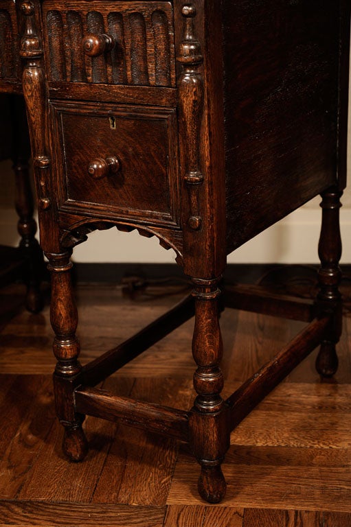 Jacobean Revival Oak Desk / Writing Table with Well-Patinated Inset Brown Leather Top Above Five Drawers on Turned Legs Joined with Box Stretchers.  England, Early 20th Century.<br />
<br />
42 inches wide x 23 inches deep x 30 inches high