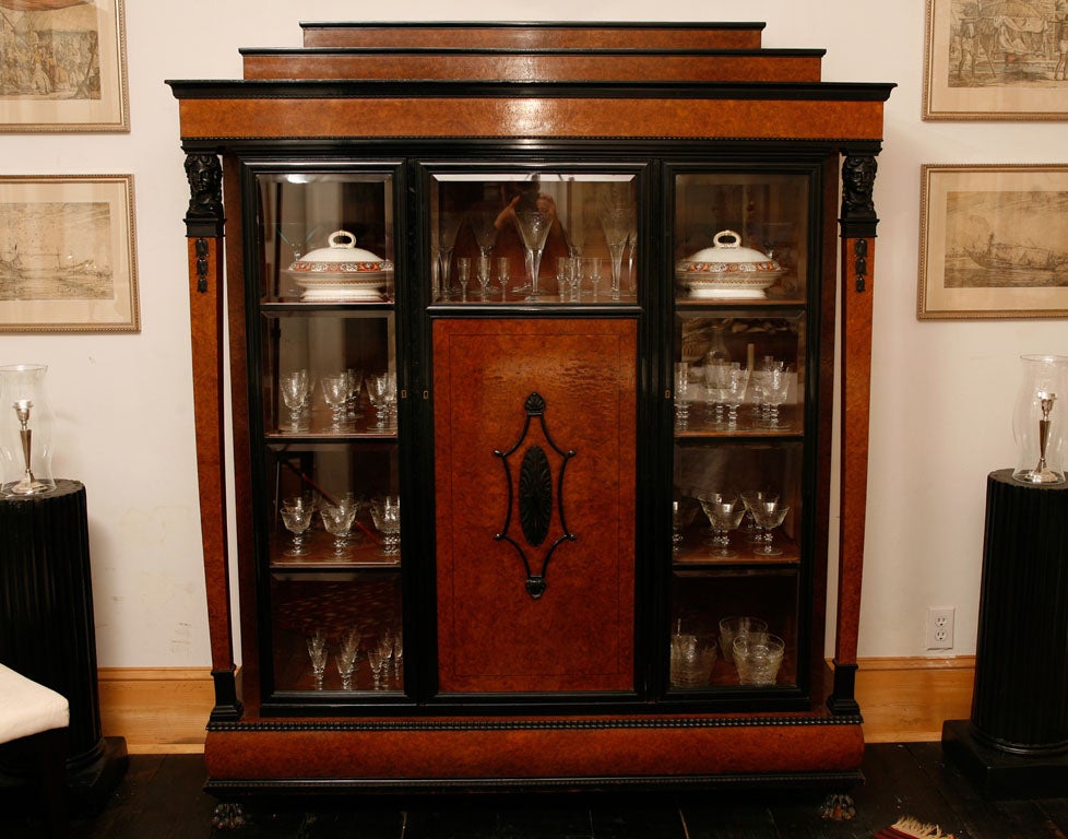 This finely made cabinet is perfect to display a collection of objects and will make a dramatic statement in any application. Veneered all over in burled aramith and contrasted with ebonized moldings and carved work the cabinet is architectural in