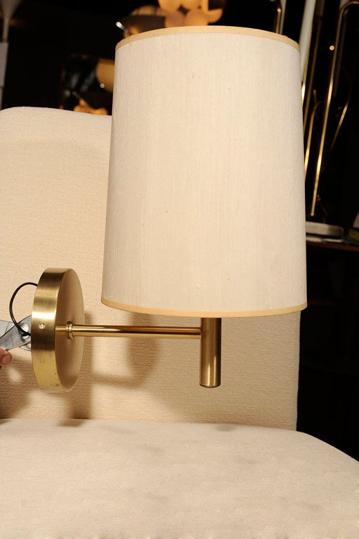 Wall lamp with brushed brass finish and custom linen shade by Nessen Studios. USA, circa 1960.<br />
<br />
Shade measurements:<br />
10 inches tall<br />
7 inches wide at top<br />
8 inches wide at bottom<br />
