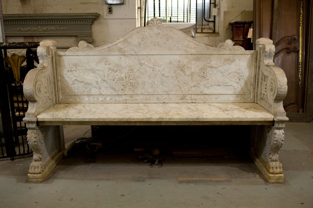 Italian carved mable neo-classical form bench with scenes of chariot races on the back, acanthus leaf decoration and paw feet.