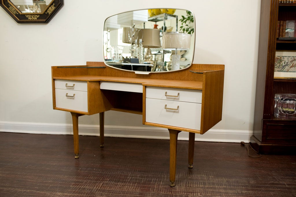 A funky and fabulous teak vanity with white lacquered drawers,<br />
brass plated handles and its original mirror.