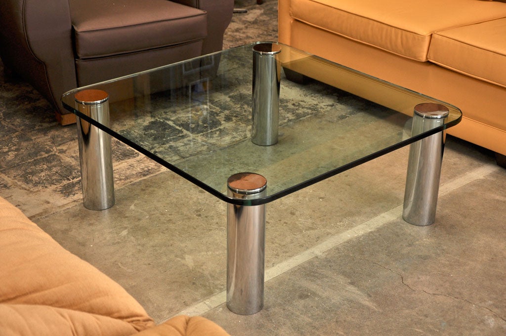 A thick rounded corner glass is set between chrome cylinder legs and mounts.
This table won the Compasso d'Oro Award design price in 1979.