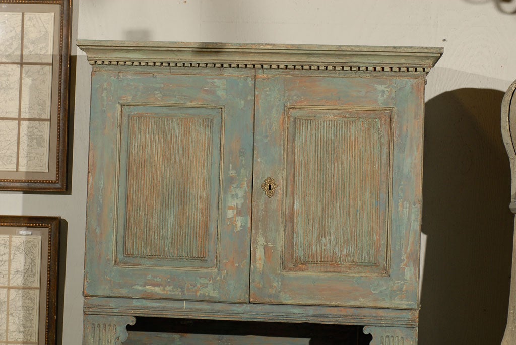 A 18th century Swedish late Gustavian cabinet with original paint. This cabinet has four doors, stationary shelves and bun feet, dentil molding and reeded doors. The feet have been replaced.