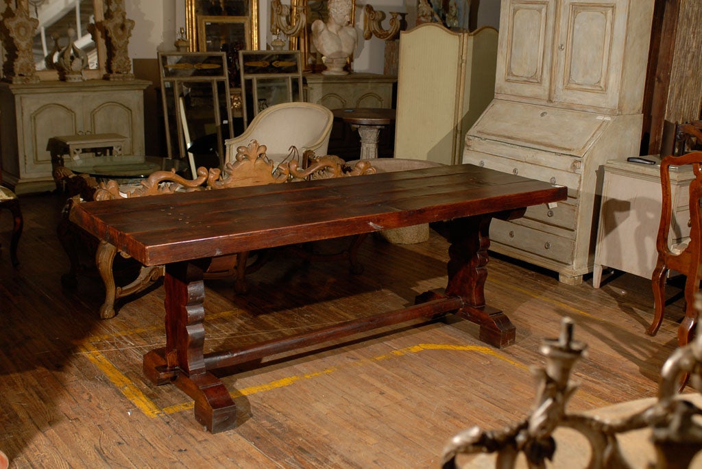 A French 19th century wooden trestle library/desk table of long and narrow shape. This elegant table has interesting legs that are carved with a curved shape. This piece features a long stretcher running from end to end. This French table would be