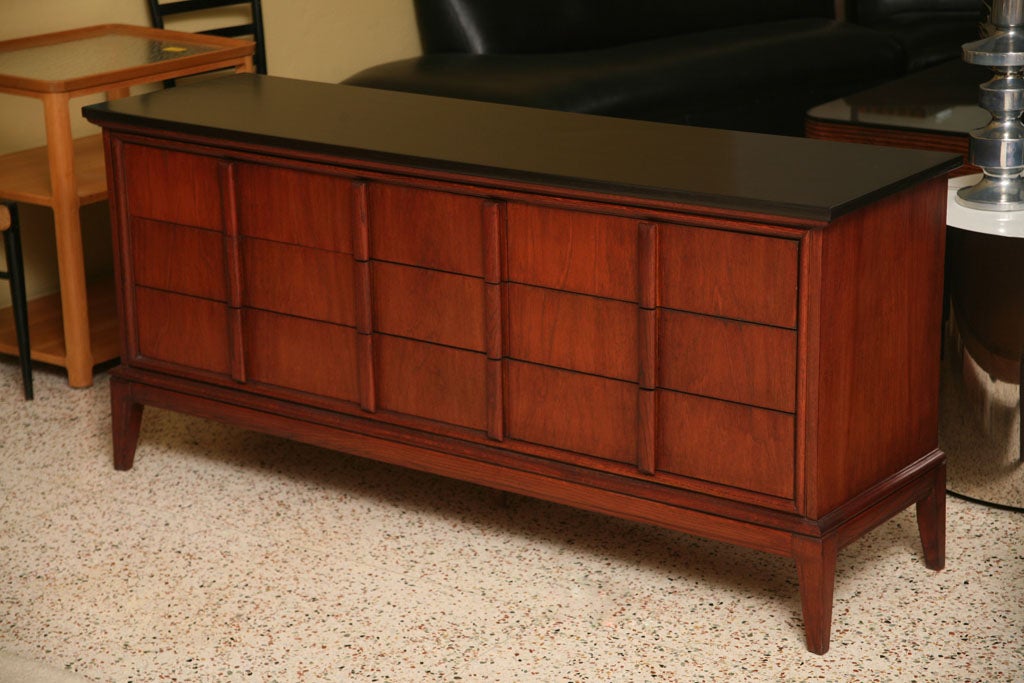 ...SOLD JUNE 2012...Strong & handsome and with striking archtectural lines, this nine drawer dresser by Dixie for Modernage features unique shaped solid wood drawer pulls creating a dynamic front facade.  In teak stained walnut with an ebonized top.