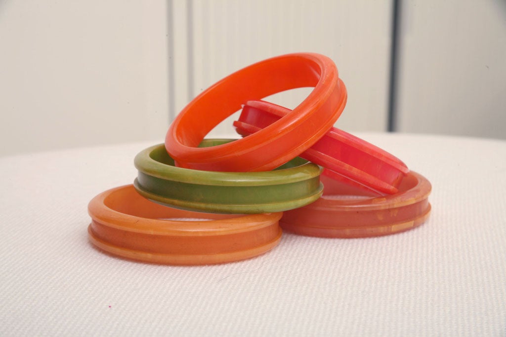 Rare set of five bakelite bangles with ridged edges. In attractive colors of green, amber, and three shades of red / orange. Stunning when worn as a set of five but always very practical as individuals. Sold exclusively as a grouping of five.