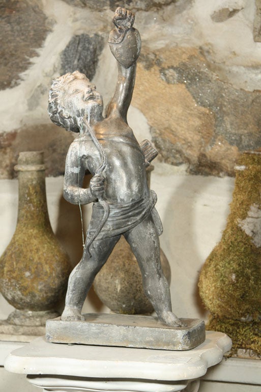 This rare lead statue of cupid, unsigned but catalogued in 1905 by the famed Arts & Crafts Artisans' group, Bromsgrove Guild, features a triumphant Cupid with quiver and copper-stringed bow, holding aloft a heart. Wonderful detailing to head,
