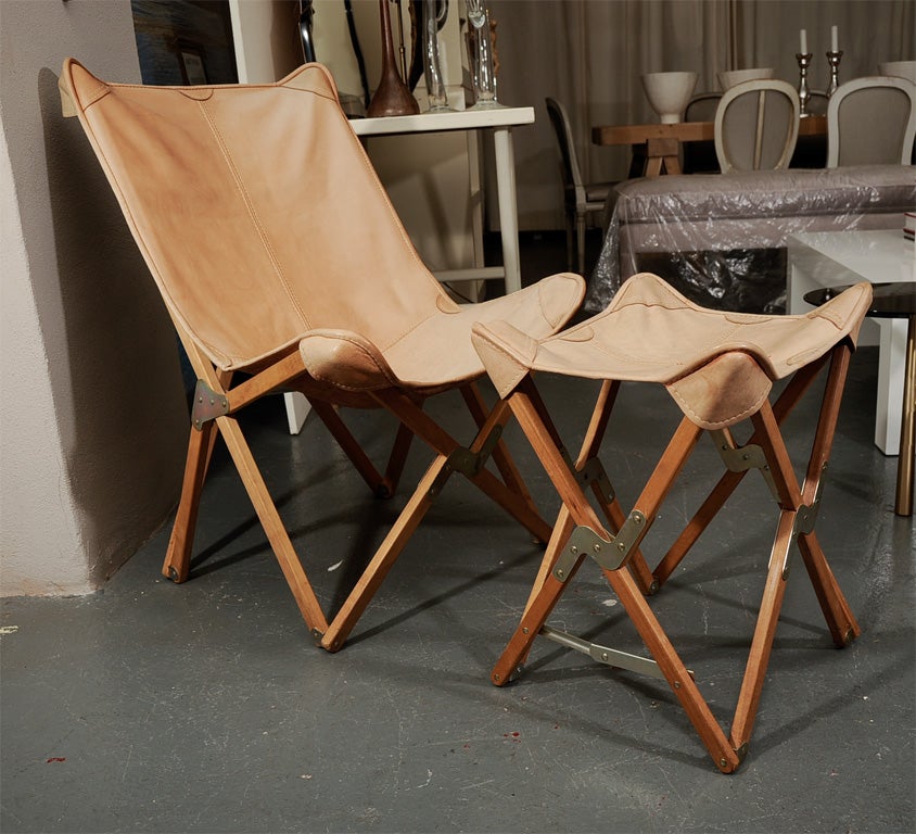 Folding butterfy chair with tan leather seat and natural wood frame. Matching folding stool.