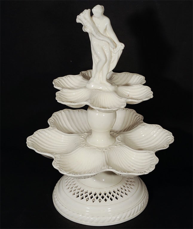 A tiered 18th century English Creamware centerpiece each tier consists of 6 shell shapes outlined with a feather edge. The base is pierced with diamonds. At the top, a figure representing the neoclassical image of 