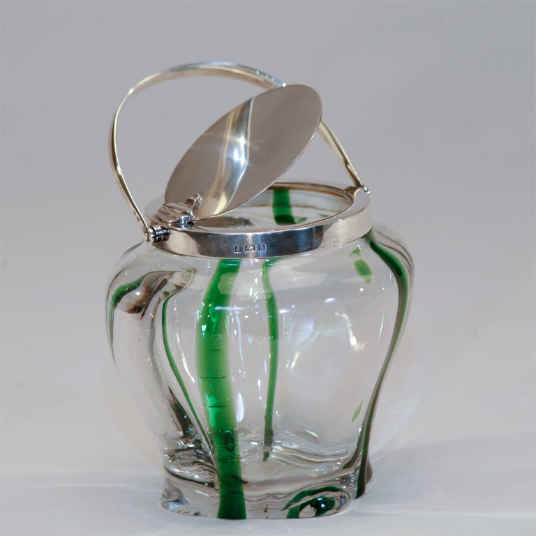 This Art Nouveau handblown crystal biscuit barrel was made by Stevens and Williams with internally decorated apple-green stripes. The top and rims are hallmarked Birmingham sterling silver, with the date code for 1902. The lid is cleverly designed