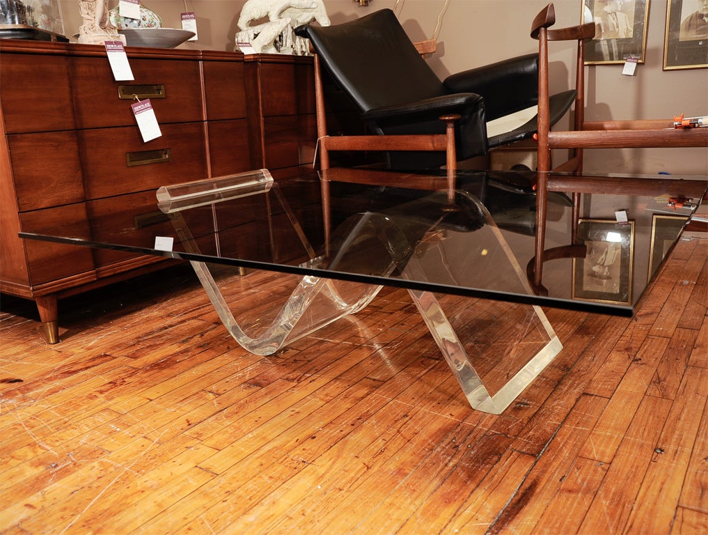 A generous slab of smoked glass sits atop a wave of Lucite.  The styling and proportions are classic 1960s modernist design.
The glass top has been replaced and is in perfect condition