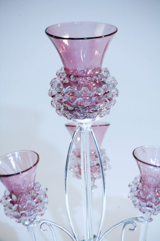 Handblown amethyst crystal trumpets fit neatly into this diminutive silver plated base to form a flower-form epergne. The unusual shade of lavender is highlighted with applied clear rigaree surrounding the vases. Each piece has a clear elongated