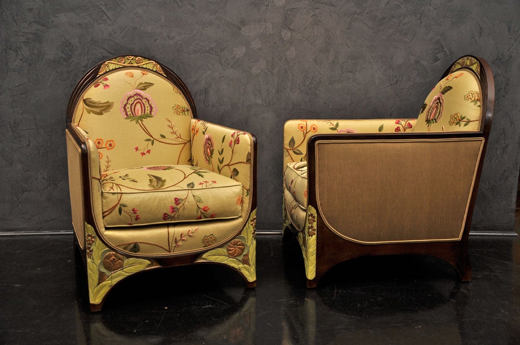 Gorgeous pair of unique salon chairs in fruitwood. Intricate detailing on frame with 24K gold leaf and green floral relief carving. Upholstered in embroidered linen and silk.